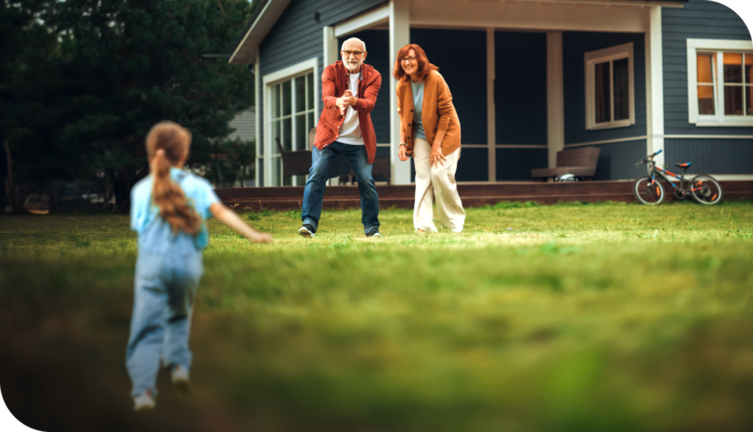 Grandparents standing in the front yard of their Wisconsin home, watching their grandchild run towards them.	